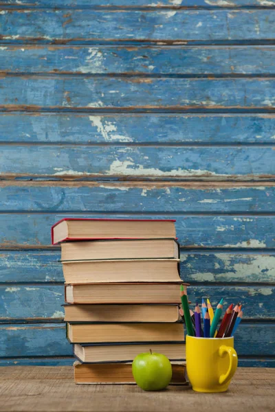 Сложенные книги с цветными карандашами и яблоками — стоковое фото