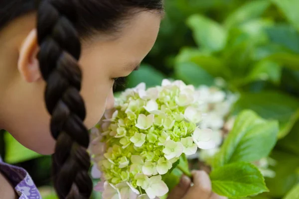Menina cheirando flores brancas e verdes — Fotografia de Stock