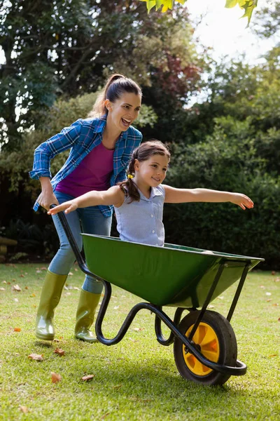 Duwen dochter moeder zitten in kruiwagen — Stockfoto