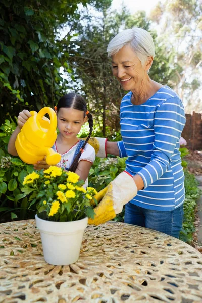 Senior vrouw en kleindochter drenken bloemen — Stockfoto