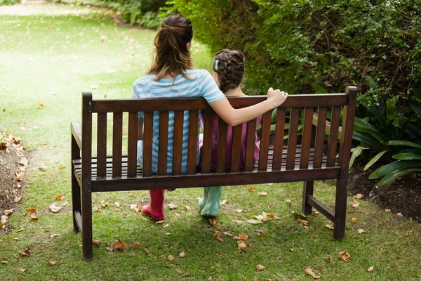 Frau und Mädchen sitzen auf Holzbank — Stockfoto