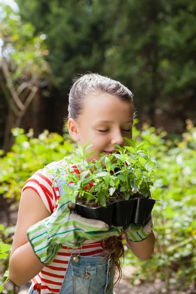 Chica oliendo plantas con los ojos cerrados — Foto de Stock