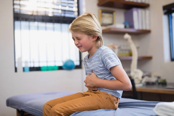Junge sitzt mit Bauchschmerzen im Bett — Stockfoto