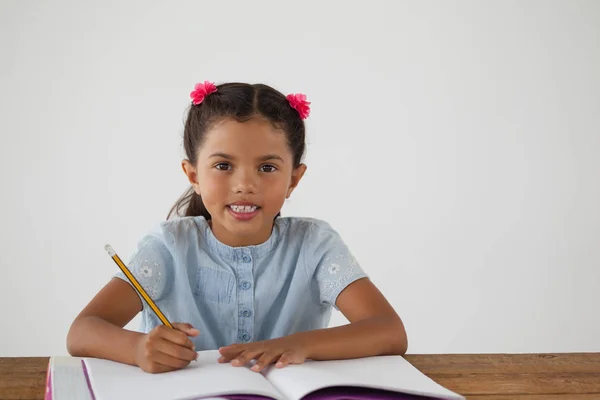 Ung flicka skriver i boken — Stockfoto