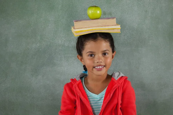 Ung flicka balansera böcker och apple — Stockfoto