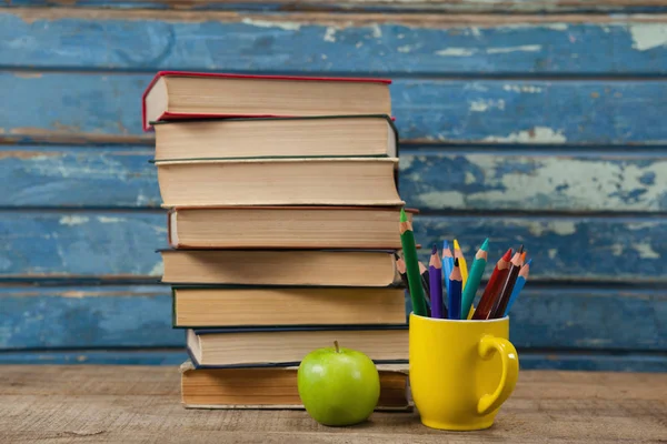 Упакованные книги с яблоками и цветными карандашами — стоковое фото