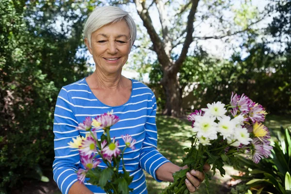 Mulher sênior olhando para flores frescas — Fotografia de Stock
