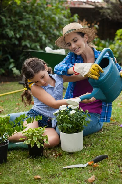 Дочь помогает матери в поливе растений — стоковое фото