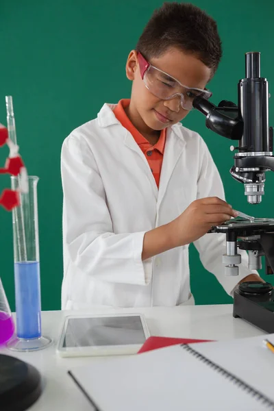 Школьник с помощью микроскопа — стоковое фото