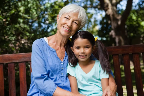 Ragazza e nonna seduta su panchina — Foto Stock