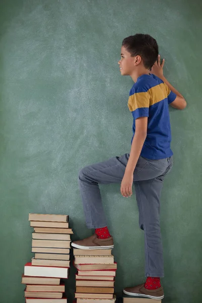 Skolpojke klättring steg staplade böcker — Stockfoto