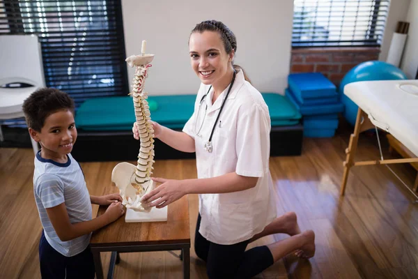 Therapist and boy kneeling with artificial spine — Stock Photo, Image