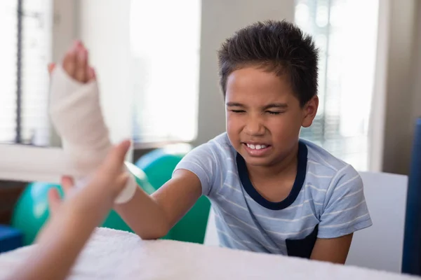 Junge sitzt, während Therapeut Verband einwickelt — Stockfoto