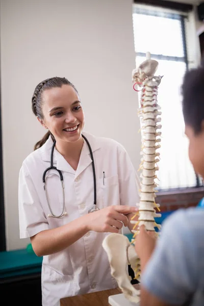 Terapeuta que explica niño mientras que señala la columna vertebral artificial —  Fotos de Stock