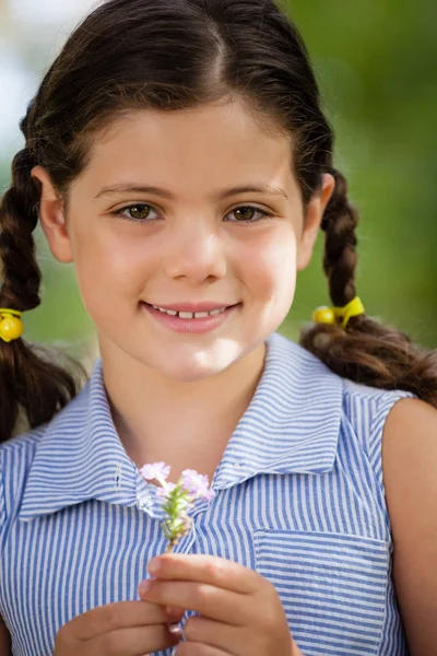 Glimlachend meisje bedrijf bloem — Stockfoto