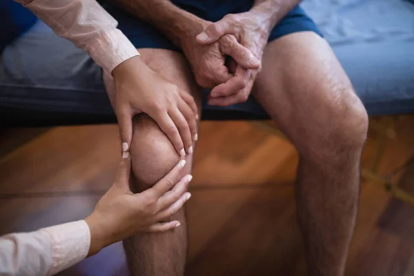 Therapist examining knee — Stock Photo, Image