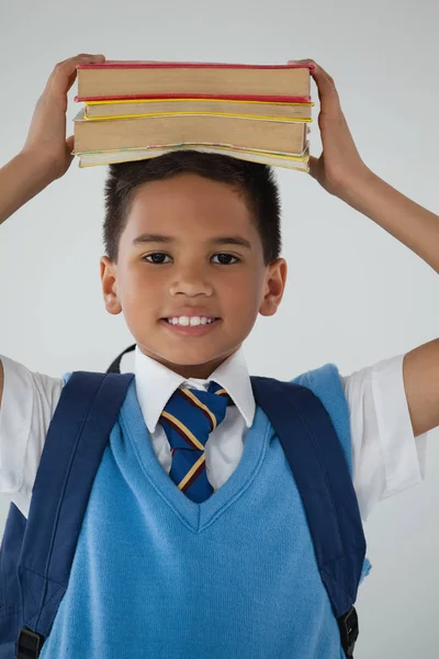 Okul çocuğu holding kitaplar kafasında — Stok fotoğraf