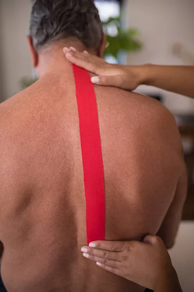 therapist applying tape on patient back