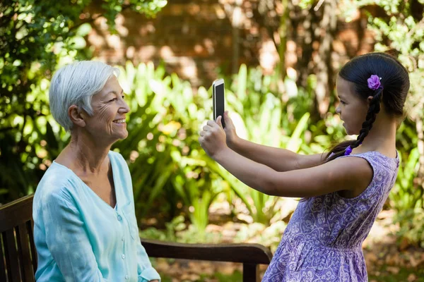 Sorridente ragazza fotografare nonna — Foto Stock