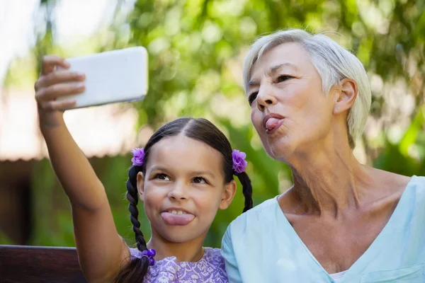 Chica y abuela sobresaliendo lengua — Foto de Stock