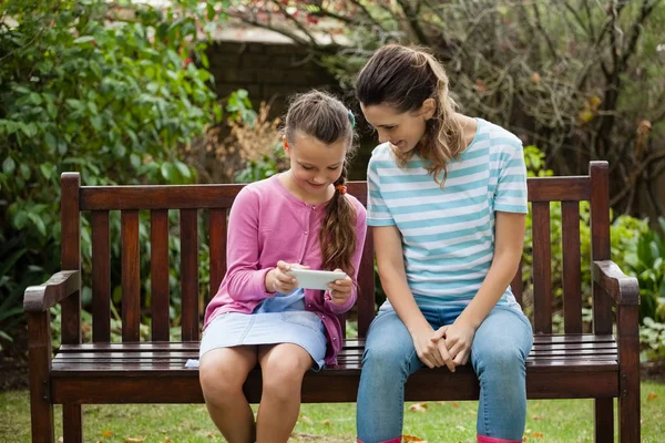 Woman sitting with girl using phone — Stock Photo, Image