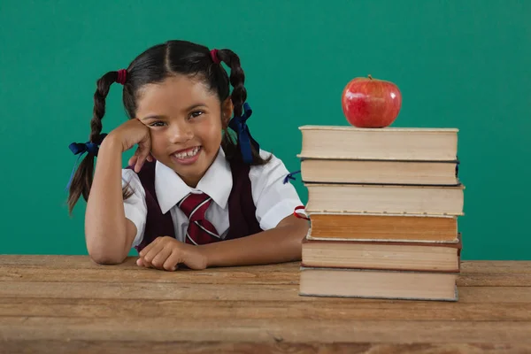 Colegiala sentada con libros apilados —  Fotos de Stock