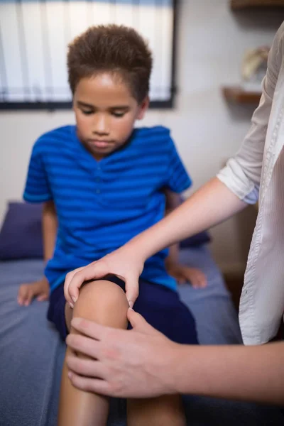 Niño mirando mientras terapeuta masaje de rodilla —  Fotos de Stock