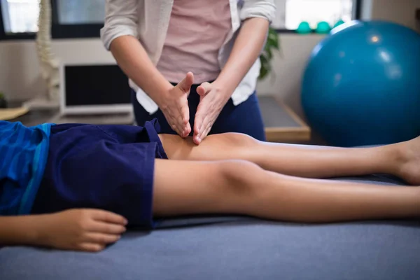 Terapeuta massageando joelho de menino — Fotografia de Stock