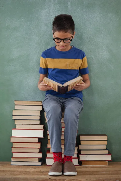Schüler sitzt auf gestapelten Büchern — Stockfoto