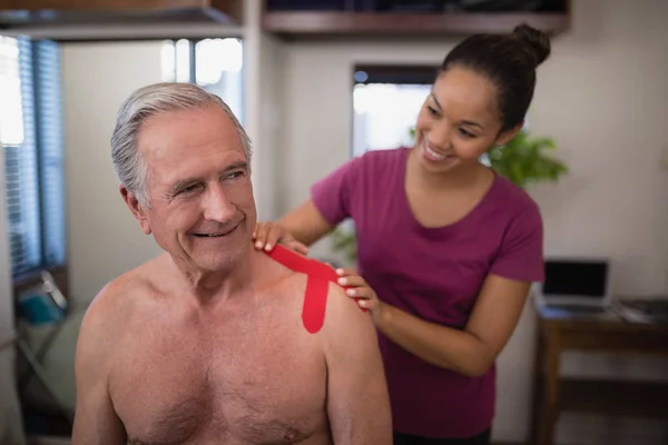 Therapist applying tape on patient — Stock Photo, Image