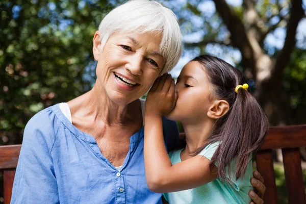 Chica susurrando en las abuelas oídos — Foto de Stock