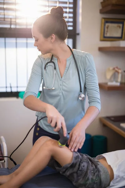 Thérapeute utilisant une machine à ultrasons sur le genou — Photo