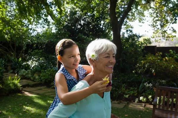 Mulher carregando neta com flores — Fotografia de Stock