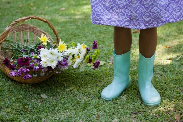 Mädchen steht mit Blumen im Korb — Stockfoto