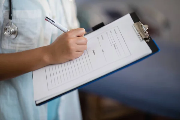 Médico escrevendo na área de transferência — Fotografia de Stock