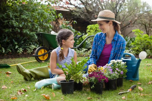 Mother and daughter sitting with potted plants — Stock Photo, Image