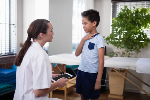 Therapist looking at boy touching neck — Stock Photo, Image