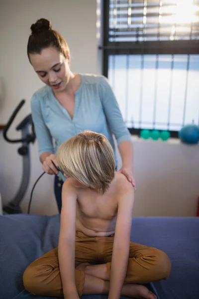 Terapeuta skanowanie ramię shirtless chłopca — Zdjęcie stockowe