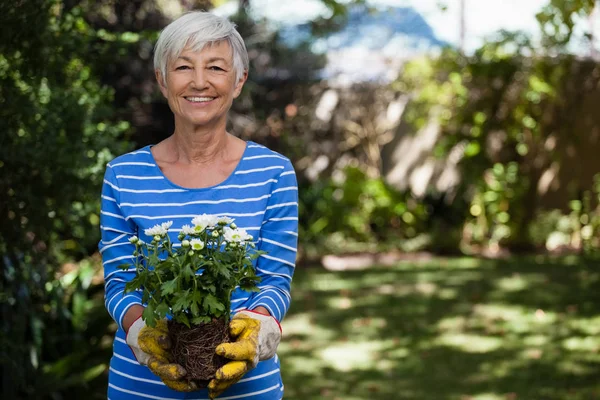 Mujer mayor de pie con flores blancas — Foto de Stock