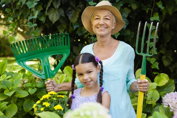 Girl and grandmother holding gardening equipment — Stock Photo, Image