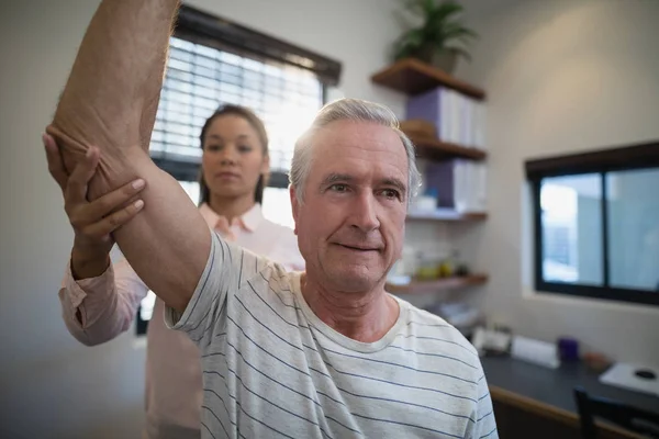 Homem olhando para longe enquanto médico examinando cotovelo — Fotografia de Stock