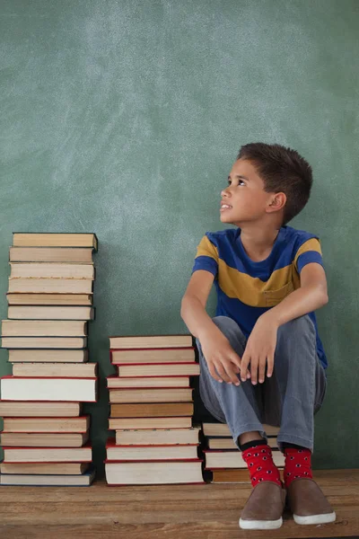 Uczniak siedzi na stos książek — Zdjęcie stockowe