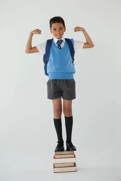 Schooljongen permanent op gestapelde boeken — Stockfoto