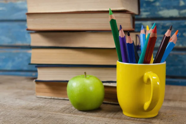 Stacked books with color pencils and apple — Stock Photo, Image