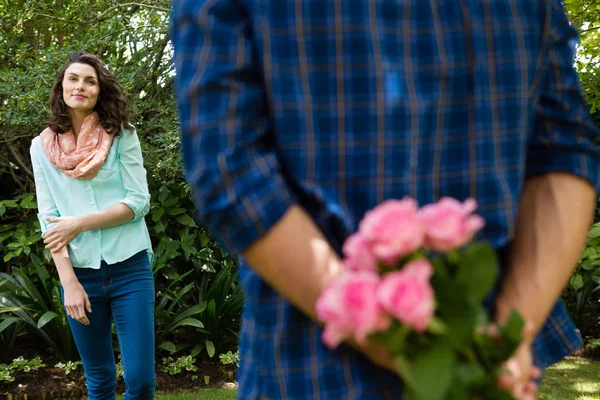 Mid-section of man hiding flowers behind back — Stock Photo, Image