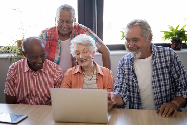 Personas mayores felices usando el portátil en la mesa — Foto de Stock