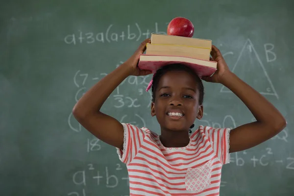 Kitap yığını apple ile kafasına tutan kız öğrenci — Stok fotoğraf