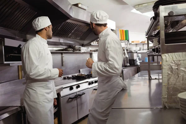Chefs interagindo uns com os outros na cozinha — Fotografia de Stock