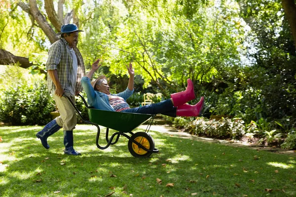 Senior mannen ger kvinnan ride i skottkärra — Stockfoto