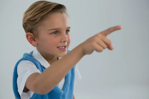 Schoolboy apontando dedo contra fundo branco — Fotografia de Stock